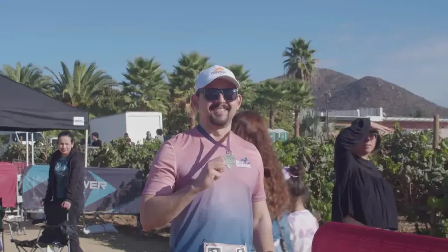 Corredor con medalla en la zona de meta del medio maratón, entre carpas y viñedos del Valle de Guadalupe
